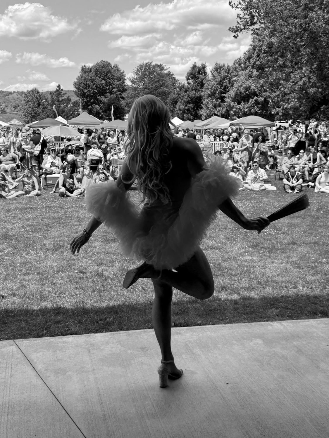 Drag performer dancing on stage at an outdoor festival